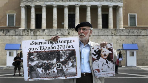 Un hombre sostiene un cartel de la canciller Angela Merkel como si fuera un miembro del partido nazi frente al Parlamento griego en la marcha por el Día de los Trabajadores en Atenas. /EFE Un hombre sostiene un cartel de la canciller Angela Merkel como si fuera un miembro del partido nazi frente al Parlamento griego en la marcha por el Día de los Trabajadores en Atenas. /EFE