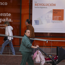 Imagen de archivo de personas pasando por delante de un anuncio de hipotecas de una entidad bancaria.